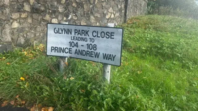 A small sign on a patch of grass that reads "Prince Andrew Way"