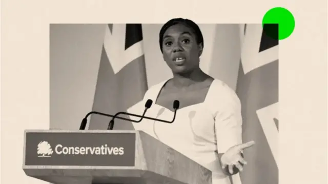 Composite image in sepia of Kemi Badenoch wearing a white dress speaking at a podium marked Conservatives at the front