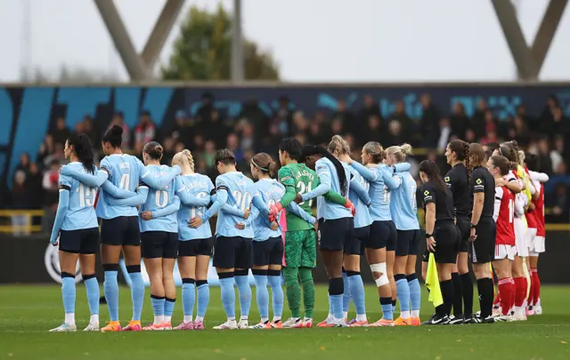 The match officials and players of Manchester City and Arsenal pause for a minutes' silence in honour of the victims of the Heaton Park Synagogue attack prior to kick-off ahead of the Barclays Women's Super League match between Manchester City and Arsenal at Joie Stadium on October 04, 2025 in Manchester, England.