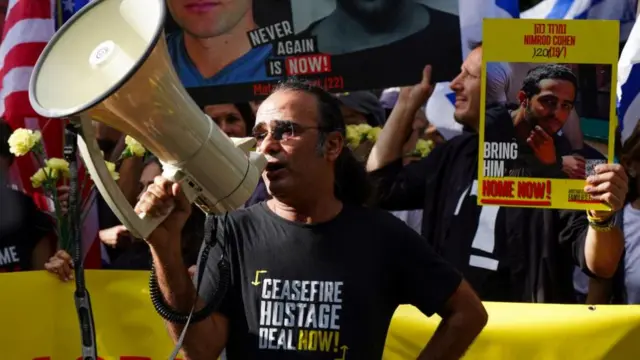 A man in a black t-shirt shouts on a megaphone