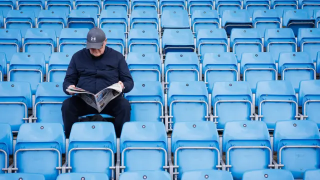 A Wycombe fan sitting reading a newspaper