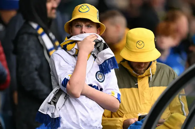 A Leeds fan with a yellow bucket hat on and a scalf