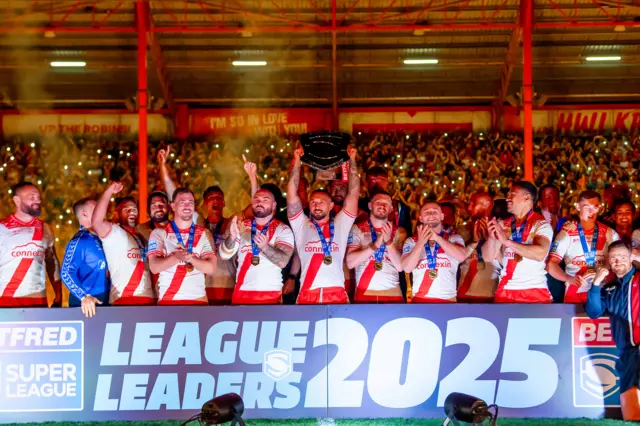Hull KR lift the League Leaders' Shield standing in front of a sign that reads 'LEAGUE LEADERS 2025'