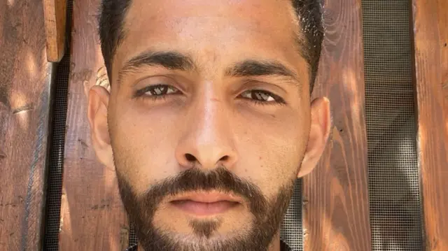Mahmoud Rostom staring straight down the barrel of the camera. He has a short brown beard