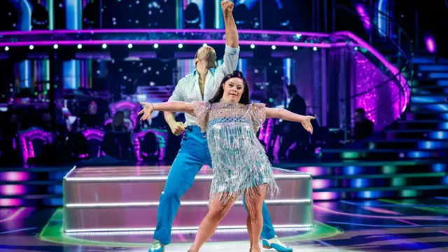 Ellie stretches her arms out as dance partner Vito punches the air behind her on the Strictly dancefloor