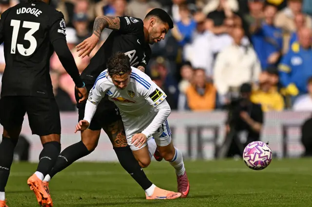 Cristian Romero fouls Leeds United's US midfielder #11 Brenden Aaronson