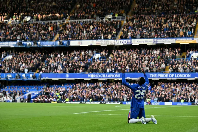 Moises Caicedo on his knees with his hands in the air