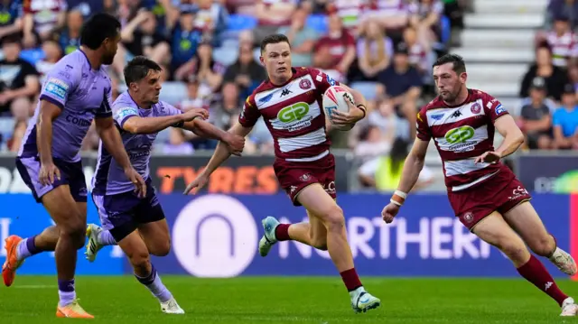 Jai Field carries the ball for Wigan with Jake Wardle to his right as two Hull KR defenders close them down