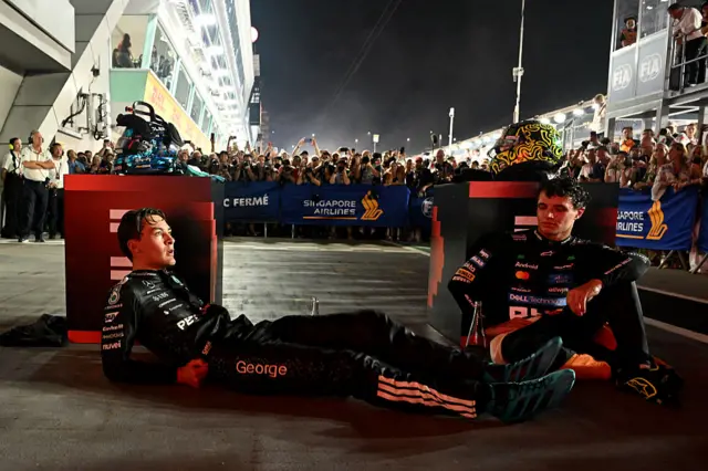 George Russell and Lando Norris sit on the floor after the hot conditions in Singapore