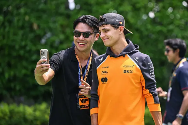 Lando Norris takes a picture with a fan in Singapore