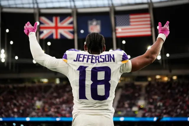 Justin Jefferson raises his arms in celebration in front of a stand packed with fans