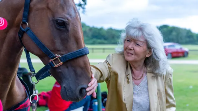 Jilly Cooper strokes the nose of a horse