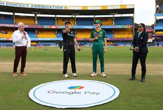 Sophie Devine of New Zealand tosses the coin alongside Laura Wolvaardt of South Africa as former professional cricket player Alan Wilkins looks on prior to the ICC Women's Cricket World Cup India 2025