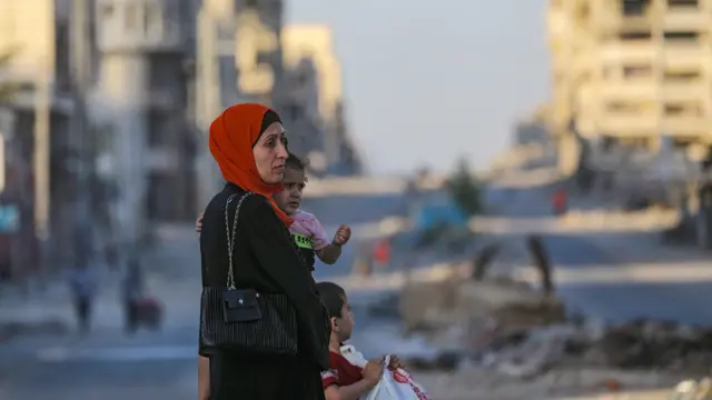 A Palestinian mother carrying her daughter stand in a street in Gaza City