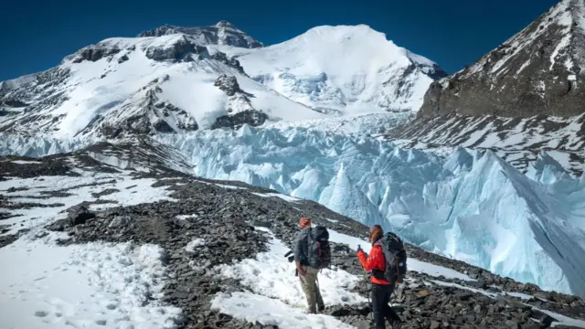 Two people with big backpacks walking along a mountainous path