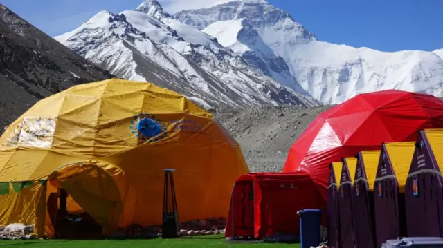 Dome tents perched against the backdrop of a mountain