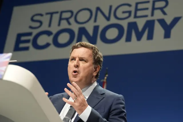 Mel Stride standing behind a podium during his speech