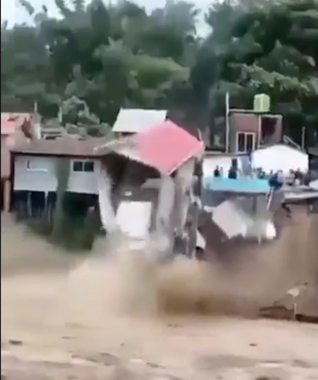 A building collapses into a swollen river in India’s West Bengal state after heavy rainfall