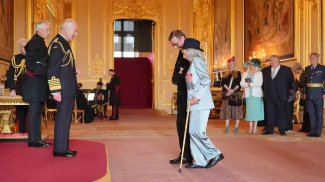 Dame Jilly Coper walks towards King Charles