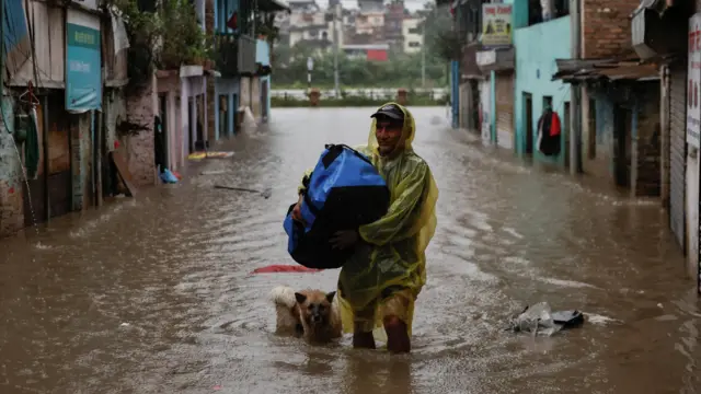 A man wades through a flooded street along the bank of overflowing Bagmati River in Nepal