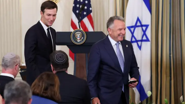 Jared Kushner and Steve Witkoff walk in front of an Israeli flag