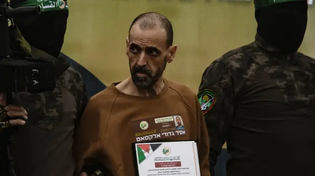 Eli Sharabi being held each arm by two masked members of Hamas