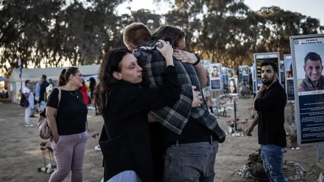 People hug in front of tributes for the victims of the Nova Music Festival