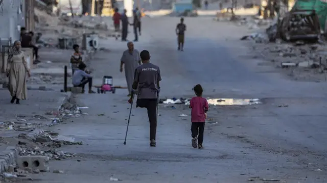 A Palestinian amputee man walks with his duaghter at Al Jalaa street during an Israeli military operation in Gaza City,