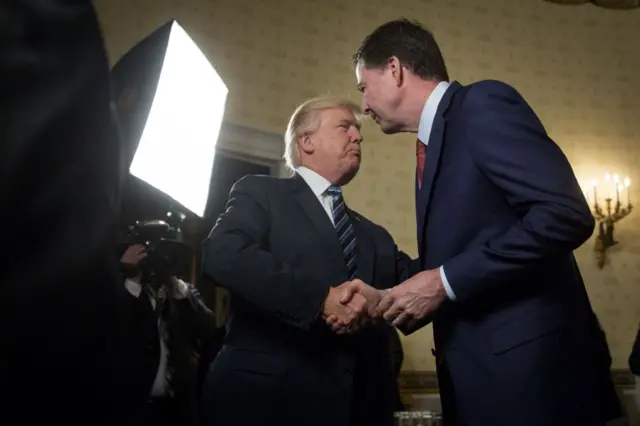 President Donald Trump, left, shakes hands with James Comey on Sunday, Jan. 22, 2017.