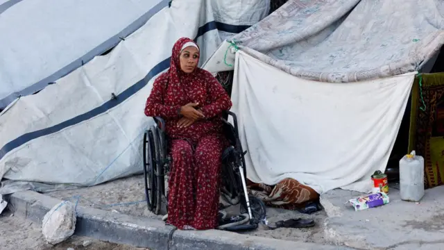 A displaced Palestinian woman, who fled her home due to the Israeli military offensive, sits in front of her tent, in Nuseirat, central Gaza Strip, October 7, 2025