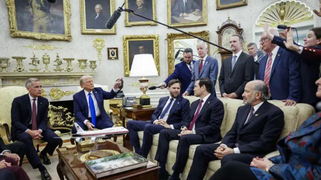 President Trump, with his hand raised and finger pointed, takes questions from reporters in the Oval Office.