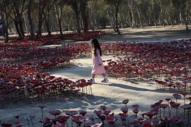 A girl walks through an installation of flowers at the site of the Nova festival where partygoers were killed and kidnapped,