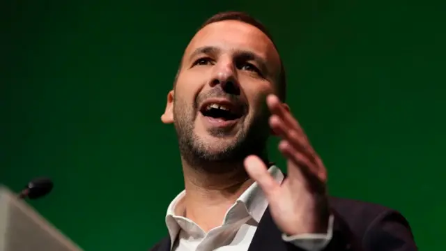 Zack Polanski gestures as he speaks from behind a podium at the Green party conference.
