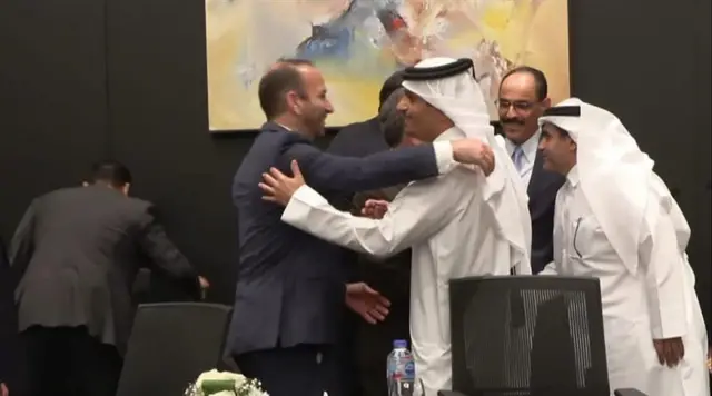 Two men embrace with other men smiling while standing behind them in Sharm El Sheikh, Egypt