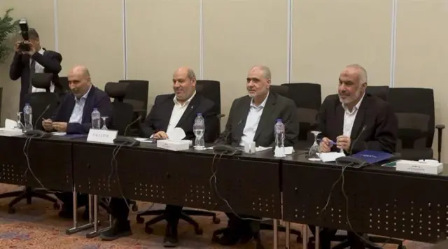 Four men in suits representing the Palestine envoy are seated behind a long table during Gaza peace talks in Sharm El Sheikh, Egypt