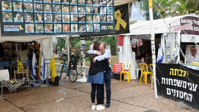 People hug next to banner with photos of hostages at the "Hostages square", after U.S. President Donald Trump announced that Israel and Hamas agreed on the first phase of a Gaza ceasefire