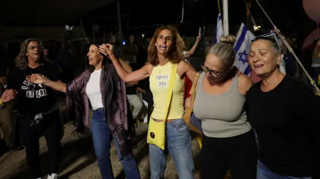 Group of women holding hands, celebrating. One has her eyes closed, and others have their arms raised in celebration