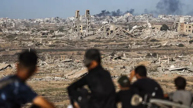 People sit and look out at destroyed city as smoke rises