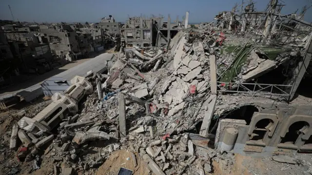 massive pile of rubble beside partially standing mosque structure