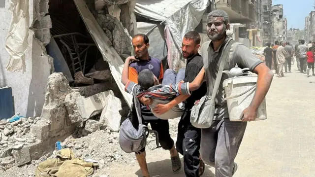 men carry an injured person out of rubble