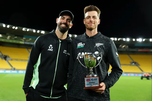 Mitchell Santner and Daryl Mitchell with a trophy.