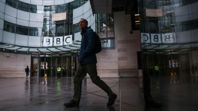 A man walks in front of BBC's New Broadcasting House