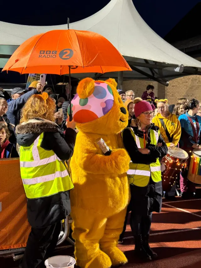 An umbrella is held for Pudsey