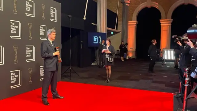 David Szalay posing on the red carpet with his Booker Prize