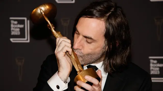 Paul Lynch kissing his Booker Prize award