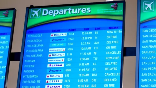 A fligth departure board at Atlanta International Airport showing many delayed and cancelled flights