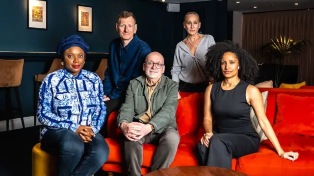 Judges Ayọ̀bámi Adébáyọ̀, Roddy Doyle and Kiley Reid sit at a red couch, while Chris Power and Sarah Jessica Parker stand behind them.