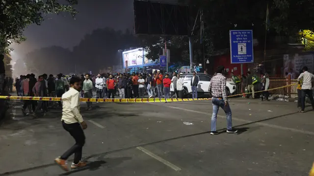 People walk past and stand behind a yellow police tape