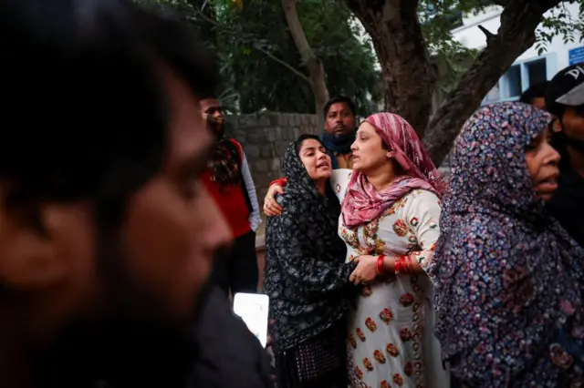 general Grieving families comfort each other as they gather outside a morgue in Delhi