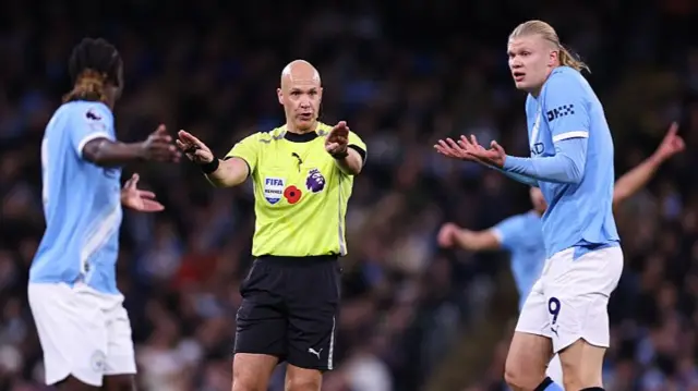 Anthony Taylor and Manchester City players Jeremy Doku and Erling Haaland